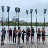 Girls crew team holding oars on a dock.