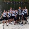 Boys rowing team posing on dock with trophy.