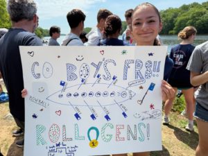Julia holding sign to cheer on the Boys Freshman 8.